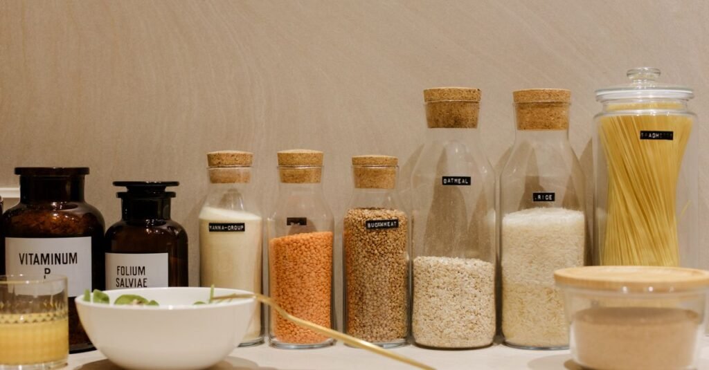 Assorted grains and pasta in labeled glass bottles on a kitchen counter