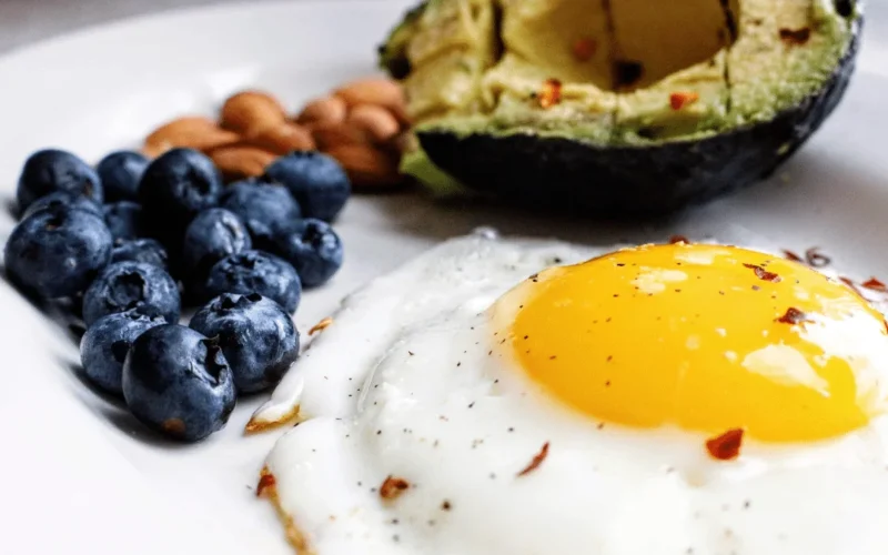 Healthy breakfast plate with egg blueberries almonds and avocado