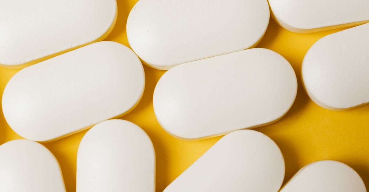 Close-up of white oval pills on a bright yellow surface