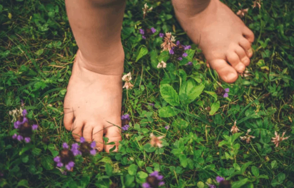 Child playing barefoot outdoors on grass and sand