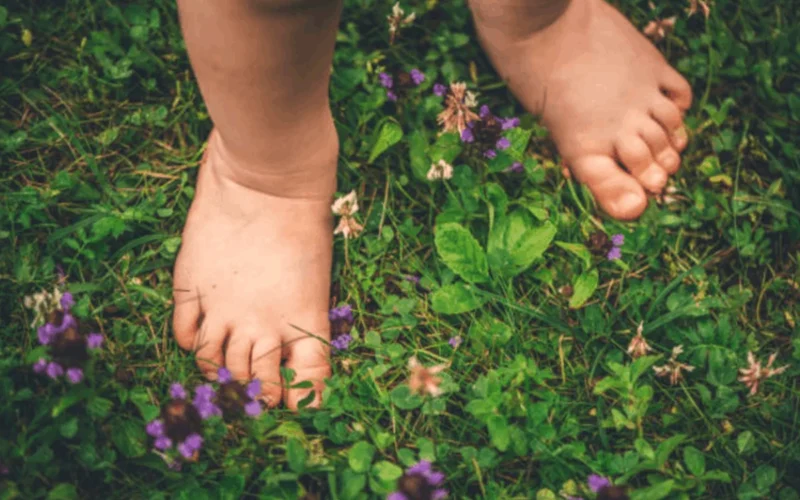 Child playing barefoot outdoors on grass and sand