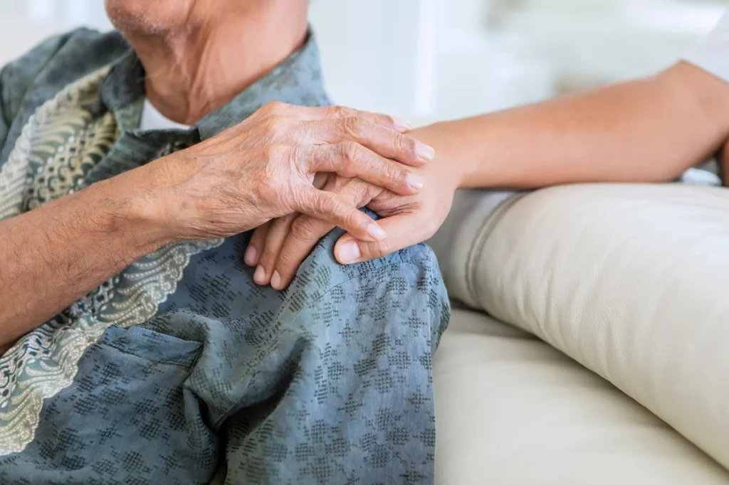 Older man holding hands with his son at home