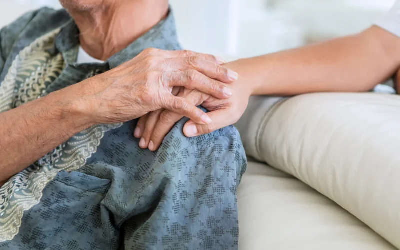 Older man holding hands with his son at home