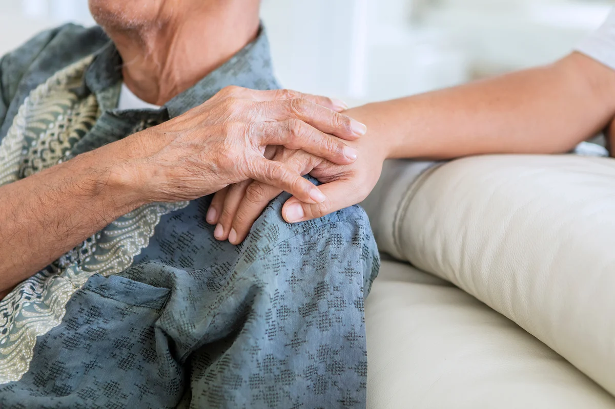Older man holding hands with his son at home