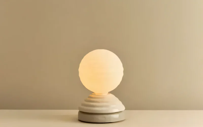Glowing wake-up light on a nightstand beside a dark bedroom