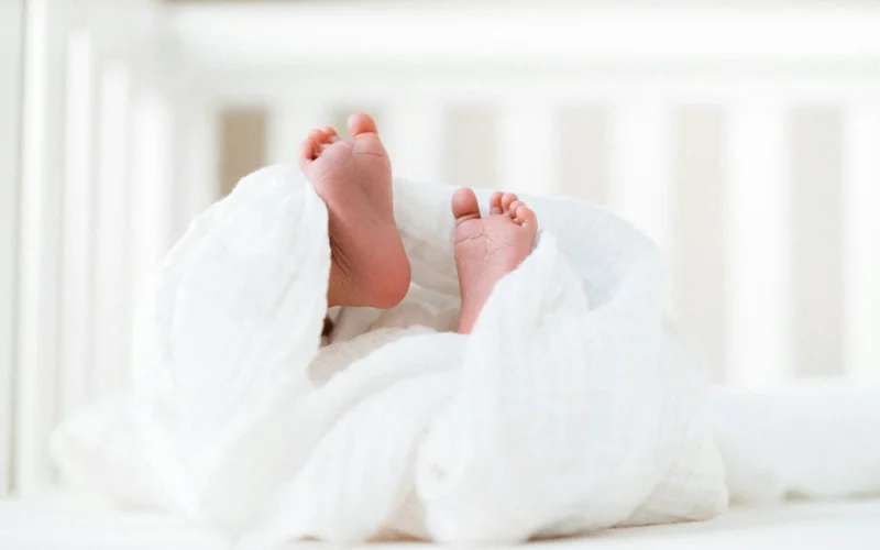 Baby's feet peeking out from a white blanket