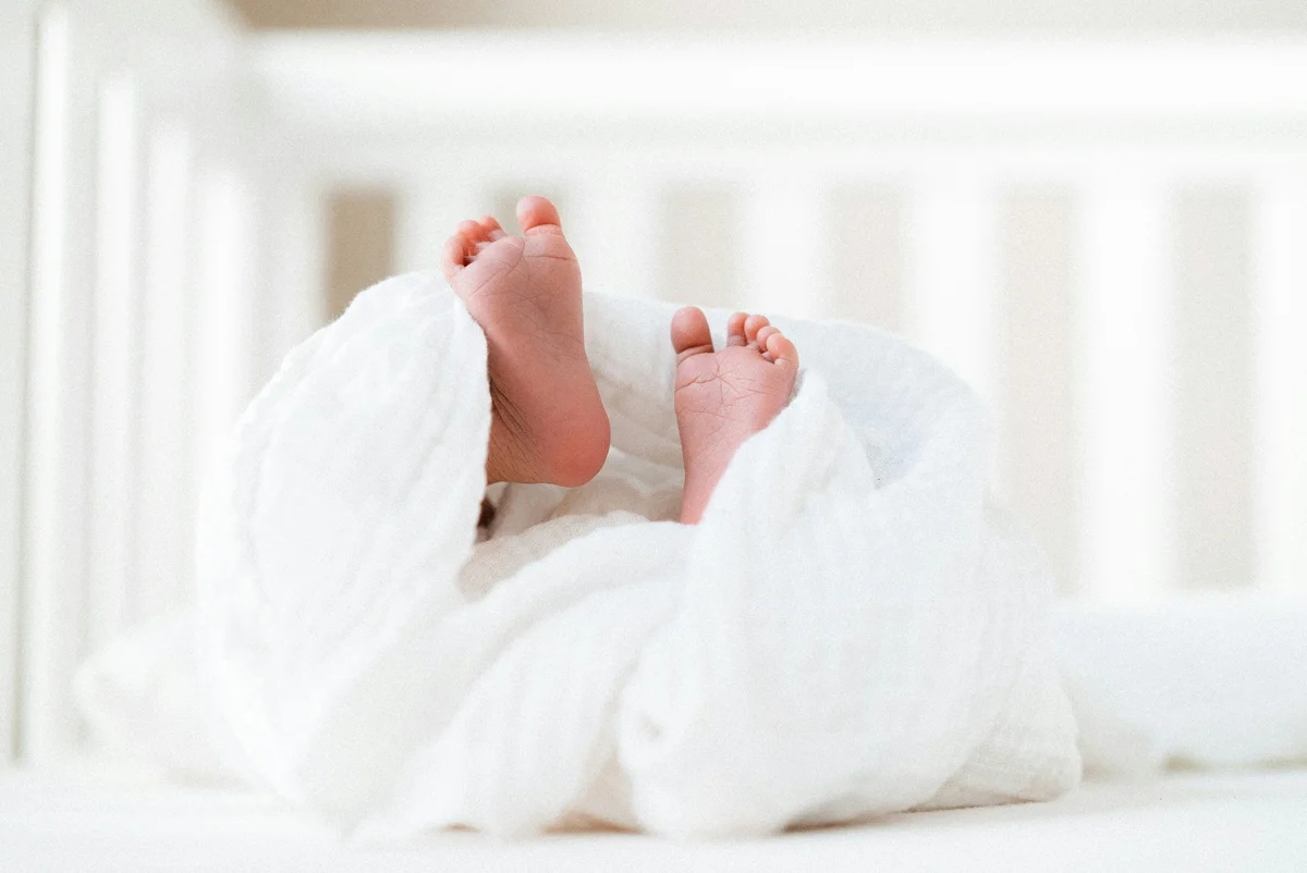 Baby's feet peeking out from a white blanket