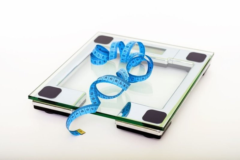 Blue measuring tape coiled on a digital bathroom scale