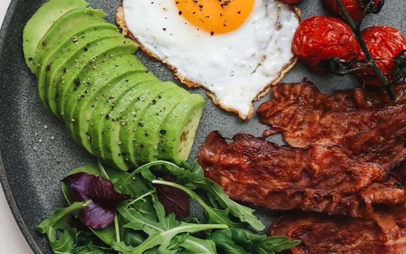 Low carb breakfast plate with eggs, avocado, bacon, and greens