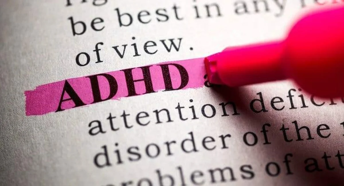 Pink highlighter marking ADHD definition in printed dictionary